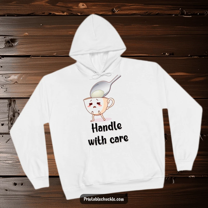 Funny hoodie featuring a startled teacup with legs running away from a massive spoon, a humorous kitchen scene.